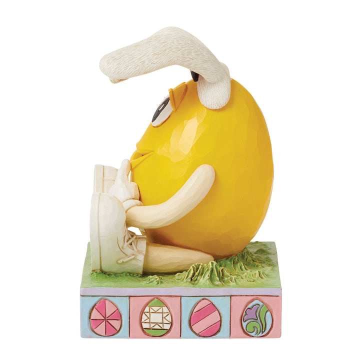 Jim Shore M&M'S: Yellow M&M Sitting With Easter Bunny Ears Figurine sparkle-castle